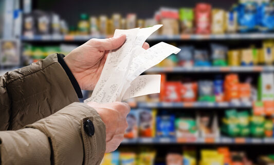 mans hands holding a long receipt in a grocery shop