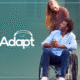 A woman pushing a man in a wheelchair, both smiling. Adapt logo.